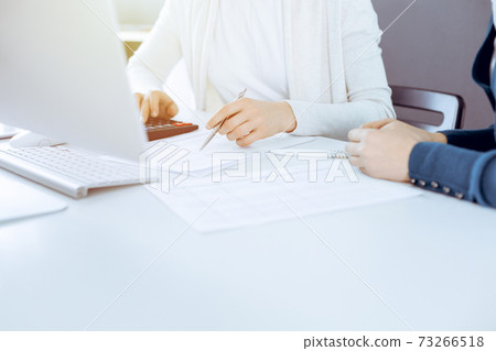 Accountant checking financial statement or counting by calculator income for tax form, hands close-up. Business woman sitting and working with colleague at the desk in office. Audit concept Accountant checking financial statement or counting by calculator income for tax form, hands close-up. Business woman sitting and working with colleague at the desk in office. Audit concept 73266518