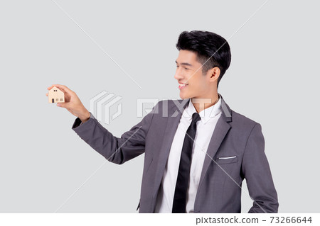 Young asian business man holding the home symbol of saving for future. Young asian business man holding the home symbol of saving for future. 73266644