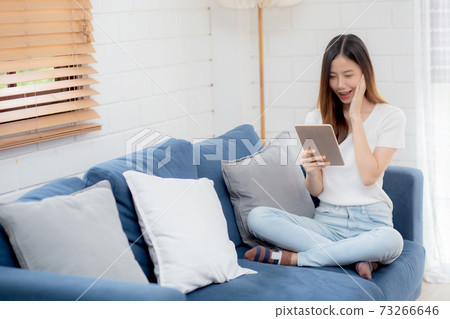 Young attractive asian woman resting using browsing tablet computer on sofa at home. Young attractive asian woman resting using browsing tablet computer on sofa at home. 73266646
