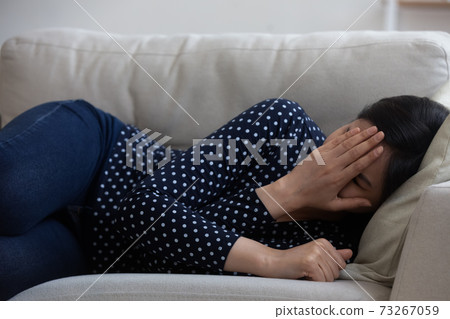 Stressed frustrated young asian mixed race woman lying on sofa. Stressed frustrated young asian mixed race woman lying on sofa. 73267059