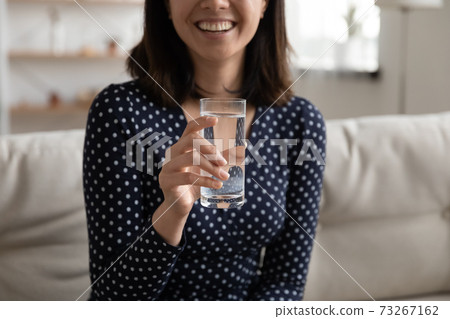 Close up smiling young asian woman holding glass of water. Close up smiling young asian woman holding glass of water. 73267162