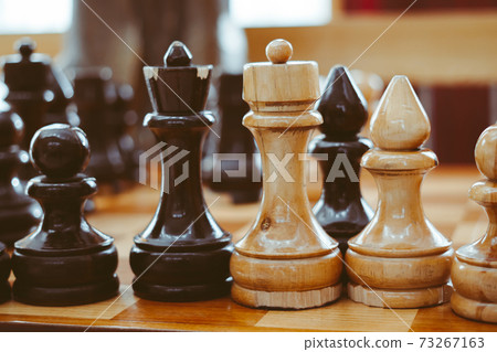hand holding a chess piece over the Board 73267163