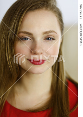 Head shot of a smart confident smiling millennial european woman standing with folded arms at home. Attractive young teenager student girl freelancer looking at camera, dressed in red 73268260