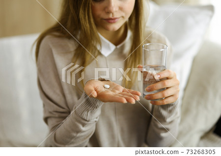 Close-up woman holding pills time to take medications, cure for headache, high blood pressure or cholesterol level remedy pain killer drugs. Stay at home concept during Coronavirus pandemic and self 73268305