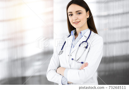 Smiling young woman-doctor is standing in sunny clinic indoors 73268511