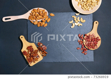 nuts on a dark table. Pecans, Cashews, almonds, peanuts. Top view with space to copy. 73268919