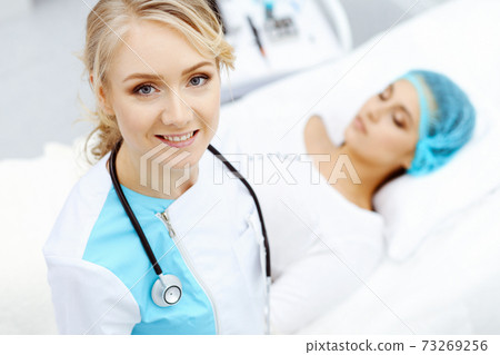Female doctor and young woman patient in hospital. Physicians examine girl lying at the bed, view from above Female doctor and young woman patient in hospital. Physicians examine girl lying at the bed, view from above 73269256