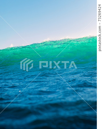 Perfect surfing wave in ocean. Breaking turquoise wave with sun light Perfect surfing wave in ocean. Breaking turquoise wave with sun light 73269424