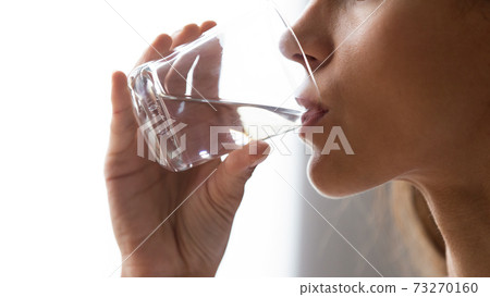 Close up woman holding glass, drinking still mineral water Close up woman holding glass, drinking still mineral water 73270160