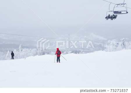 downhill skiers and chairlift in a winter hilly landscape 73271837