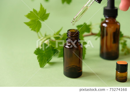 Essential oil falling from a glass dropper on the background of other medications 73274168