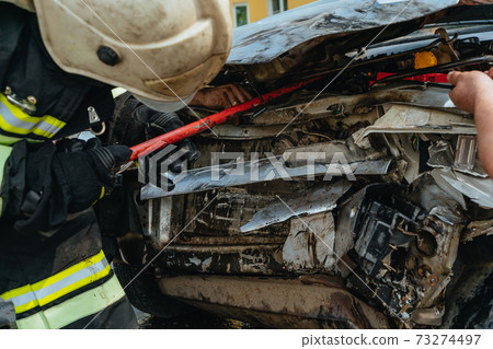 Rescuers rescue victims from a wrecked car Rescuers rescue victims from a wrecked car 73274497