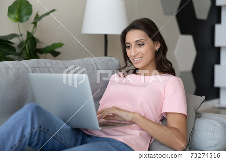 Happy ethnic woman relax at home using laptop 73274516