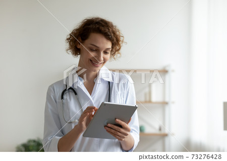 Happy young professional general practitioner using digital computer tablet. Happy young professional general practitioner using digital computer tablet. 73276428