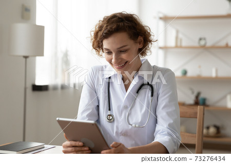 Happy 35s female doctor using software application on digital tablet. Happy 35s female doctor using software application on digital tablet. 73276434