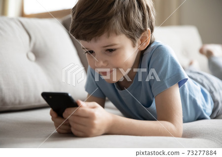 Happy little boy have fun using smartphone Happy little boy have fun using smartphone 73277884