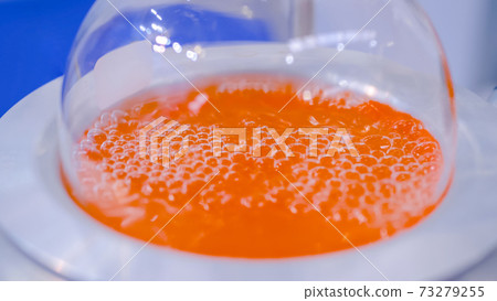 Laboratory round bottom flask heating equipment - boiling orange liquid: closeup Laboratory round bottom flask heating equipment - boiling orange liquid: closeup 73279255