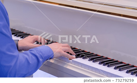 Man hands playing on white grand piano on concert - close up Man hands playing on white grand piano on concert - close up 73279259