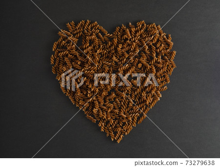 Top view of heart made of buckwheat pasta fusilli on dark background. Healthy lifestyle concept 73279638