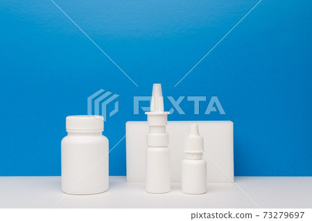 Medication bottle, nose spray and eye drops on white table against blue background with copy space 73279697