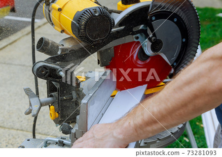 A worker cuts a wooden molding board at a construction circular saw A worker cuts a wooden molding board at a construction circular saw 73281093