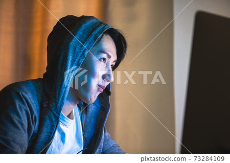 一個男人戴兜帽，晚上玩電腦 73284109
