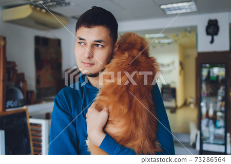 young man holding maine coon ginger cat. 73286564
