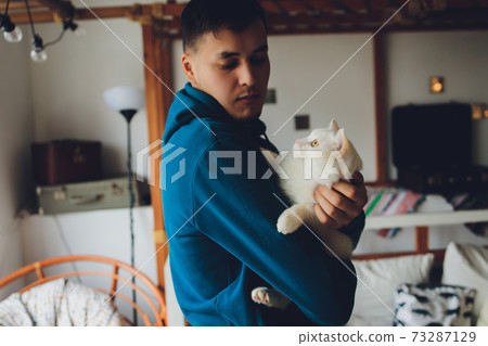 young man holding a white cat close-up. young man holding a white cat close-up. 73287129