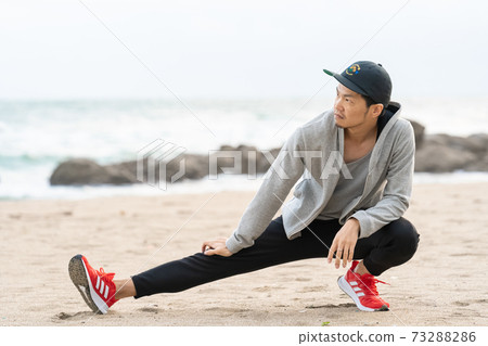 A man stretching on the beach A man stretching on the beach 73288286