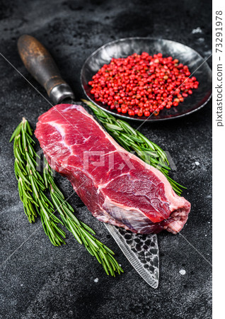 Fresh raw marbled beef meat sirloin steak on a knife. Black background. Top view 73291978