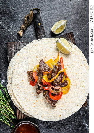 Beef Steak Fajitas with tortilla, mix pepper and onion traditional Mexican food. Black background. Top view Beef Steak Fajitas with tortilla, mix pepper and onion traditional Mexican food. Black background. Top view 73292193