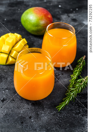 Freshly squeezed mango juice in a glass. Black background. Top view 73292195