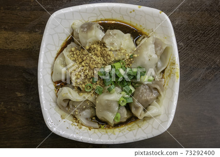 The close up of Taiwanese traditional steamed spicy stinky tofu wontons cuisine on old wooden table at food night market restaurant in Taipei, Taiwan. 73292400