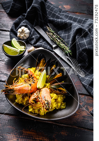 Seafood paella with prawns, shrimps, mussels. Black wooden background. Top view 73292478