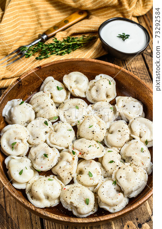 Homemade Russian Dumplings Pelmeni with beef and pork meat in a wooden bowl. wooden background. top view Homemade Russian Dumplings Pelmeni with beef and pork meat in a wooden bowl. wooden background. top view 73292584