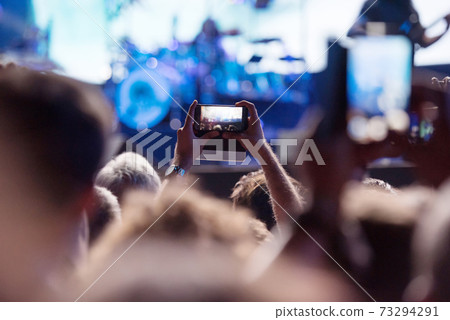 People taking photos with smart phones during a mconcert People taking photos with smart phones during a mconcert 73294291