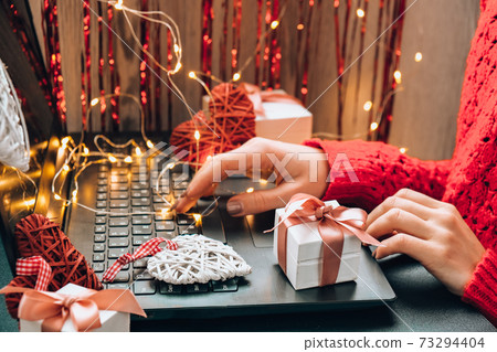Online shopping concept with woman hand typing computer keyboard. Valentines day international Women's day and Christmas hearts gift box. Presents 73294404