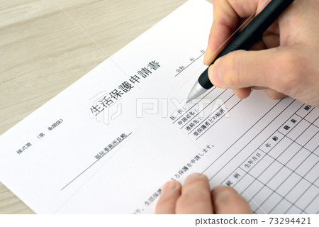 Hands of the person who fills out the welfare application form 73294421