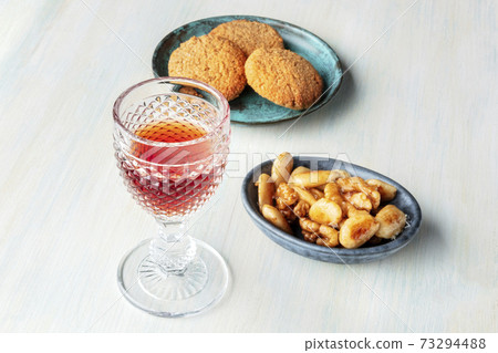 A photo of a glass of sweet wine with cookies and nuts A photo of a glass of sweet wine with cookies and nuts 73294488