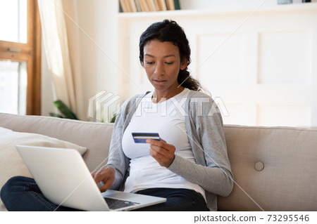 Focused young african american woman shopping online. Focused young african american woman shopping online. 73295546