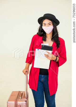 tourist in medical mask hold luggage. Holiday maker 73296033