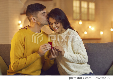 Young smiling woman getting proposal with ring from her boyfriend during Valentines day celebration Young smiling woman getting proposal with ring from her boyfriend during Valentines day celebration 73298509