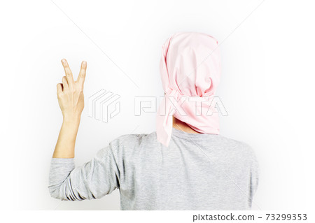 Woman with a pink headscarf for cancer performing the victory symbol 73299353