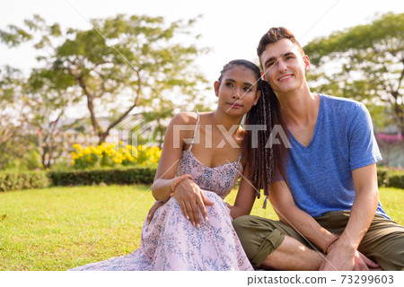 Portrait of young multi ethnic couple relaxing together at the park Portrait of young multi ethnic couple relaxing together at the park 73299603