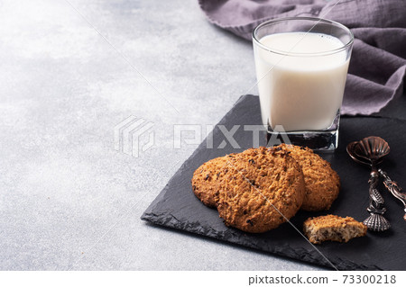 Homemade cookies cereals oats and a glass of milk on the grey concrete table. Copy space. Homemade cookies cereals oats and a glass of milk on the grey concrete table. Copy space. 73300218