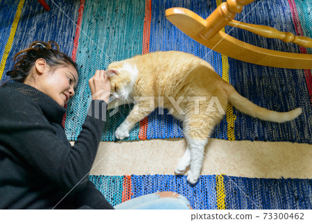 Portrait of happy young beautiful Asian woman petting cat at home 73300462