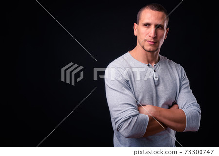 Muscular man with arms crossed against black background 73300747