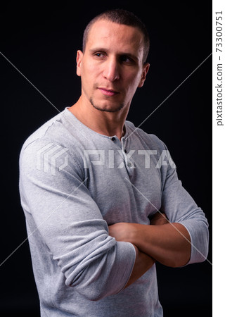 Muscular man with arms crossed against black background Muscular man with arms crossed against black background 73300751