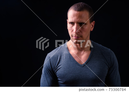 Face of man with short hair against black background Face of man with short hair against black background 73300784