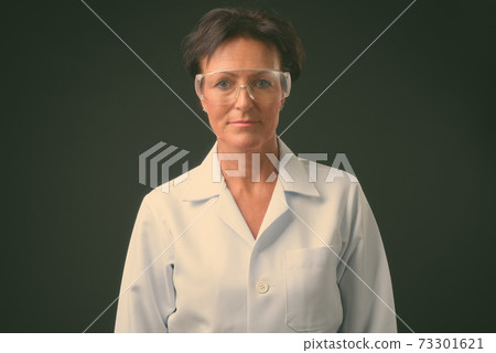 Mature beautiful woman doctor with short hair against black background Mature beautiful woman doctor with short hair against black background 73301621